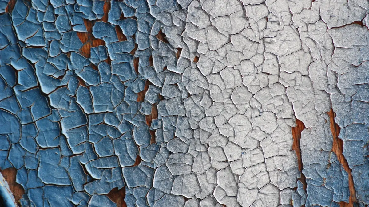 Parede com tinta azul e branca rachada e descascando